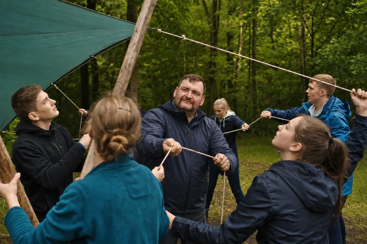 Manuel Bauer im Regenmantel bei einer Teamaufgabe im Wald